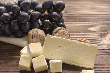 brie cheese with nuts and grape on wooden background