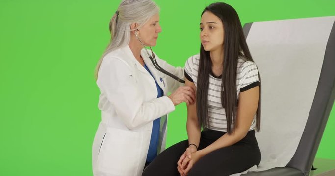 A young girl receives her check-up from a medial professional on green screen. On green screen to be keyed or composited. 