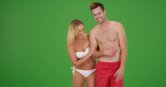 Cute millennial couple standing by the beach laughing on green screen. On green screen to be keyed or composited. 