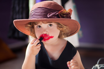 Little girl trying mothers lipstick. Growing up concept.
