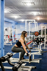 Fototapeta na wymiar A woman wearing sportswear performs exercises in the gym