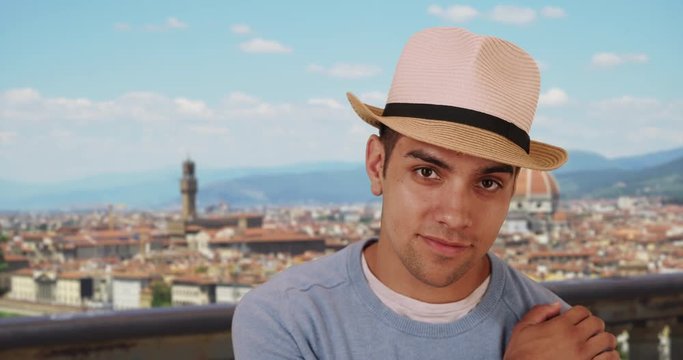Happy stylish Latino male in summer hat smiling and laughing in Florence