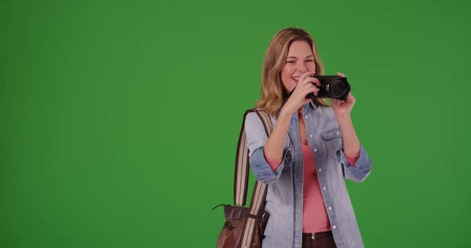 Cheerful female tourist taking picture with camera on green screen. On green screen to be keyed or composited.