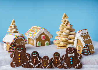 home made delicious traditional gingerbread village and gingerbread man family blue background.