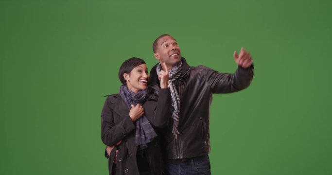 A black man and woman act playfully on green screen. On green screen to be keyed or composited. 