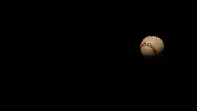 Slow motion baseball flying through camera frame.