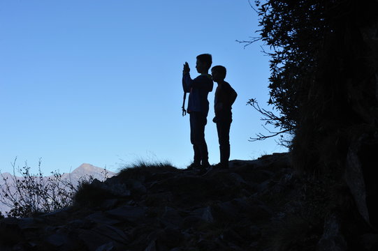 Zwei junge Wanderer fotografieren die Landschaft mit dem Smartphone (Silhouetteneffekt)
