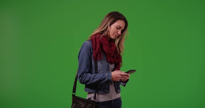 Trendy millennial girl messaging on smartphone on green screen. On green screen to be keyed or composited.