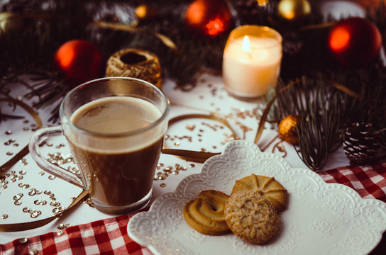Cup of coffee, candle and cookies on table with winter and christmas decorations. 