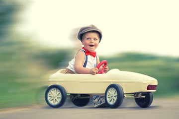 kleiner Junge mit Tretauto im Frühling