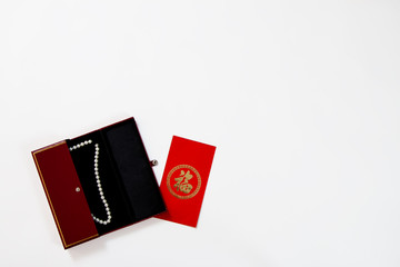Chinese new year red envelope with wish and gift box jewelry pearl on isolated top view. flaylay