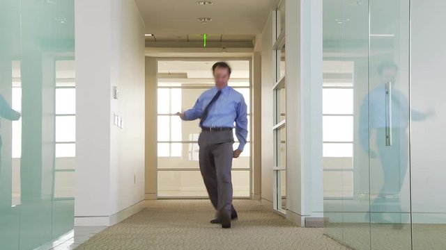 Businessman walking down office hallway with confidence