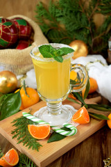 Yellow cocktail in an Irish mug decorated with sugar border and mint surrounded by Christmas attributes