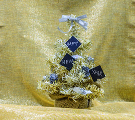 Golden and silver Christmas tree with black cards that say Happy New Year