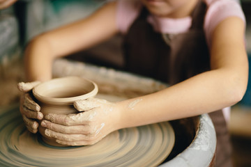 Hands of young potter, close up hands made cup on pottery wheel