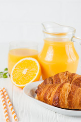 Freshly baked croissant, orange juice, fresh fruits, jam on white wooden background. French breakfast. Fresh pastries for morning. Delicious dessert. Closeup photography. Vertical banner