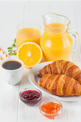 Freshly baked croissant, orange juice, fresh fruits, jam on white wooden background. French breakfast. Fresh pastries for morning. Delicious dessert. Closeup photography. Vertical banner