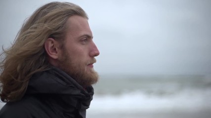 Portrait in profile of manly male explorer with long brown hair taking pleasure in force of nature breathing fresh cold air looking ahead in slow motion - Powered by Adobe