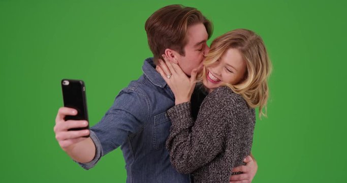 Happy engaged couple taking picture with cell phone on green screen. On green to be keyed or composited. 