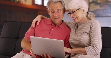 Closeup of senior couple using laptop at home - Powered by Adobe