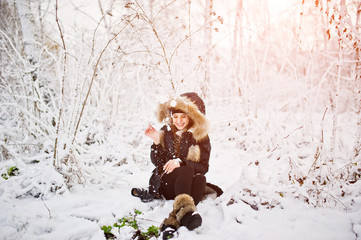 Beautiful brunette girl in winter warm clothing. Model on winter jacket and black hat.