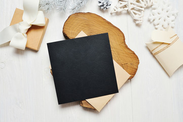 Mockup Christmas black greeting card letter in envelope and gift with white tree, flatlay on a white wooden background, with place for your text