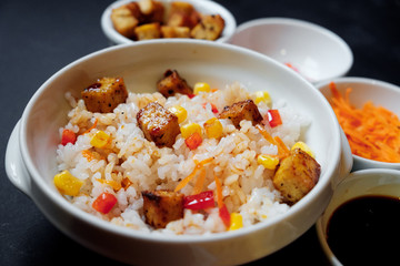 vegetarian rice salad with tofu and brown rice on black background.