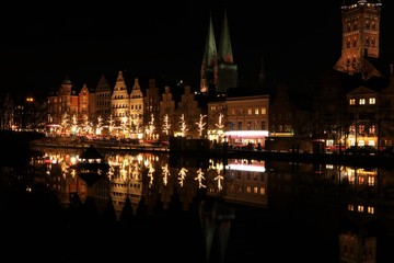 Fototapeta na wymiar historic gable houses and church towers in festive christmas lights in the medieval old town of Lübeck at night