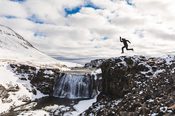 Funny man jumping next to waterfall in Iceland