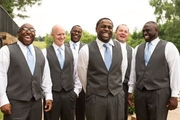 Groom and groomsmen smiling at a wedding.