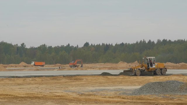 Grader or bulldozer leveling sand base on road. Construction machinery works on runway construction of national airport Minsk, MSQ. Concreting of airport runways roads, highway