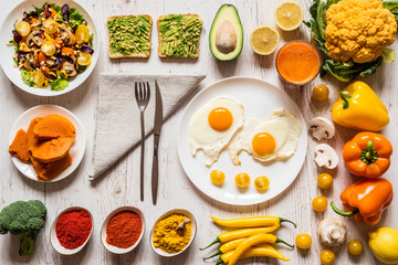 Healthy food for Breakfast. Fried eggs, vegan avocado sandwiches, veggies salad, boiled pumpkin, carrot fresh juice and Different colorful organic vegetables and spices