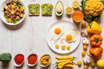 Healthy food for Breakfast. Fried eggs, vegan avocado sandwiches, veggies salad, carrot fresh juice and Different colorful organic vegetables and spices