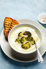 broccoli cheese soup and fresh grilled bread with sour cream and black pepper on blue background