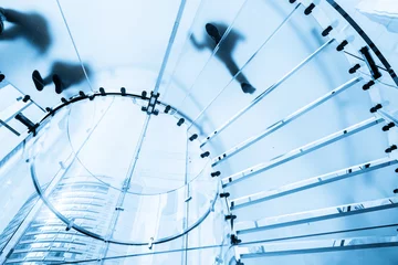 Fotobehang Trappen Silhouettes of people walking on a glass spiral staircase  © onlyyouqj