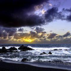 Obraz premium Sunrise over the ocean before storm - black volcanic beach near El Golfo, Lanzarote, Canary Islands, Spain