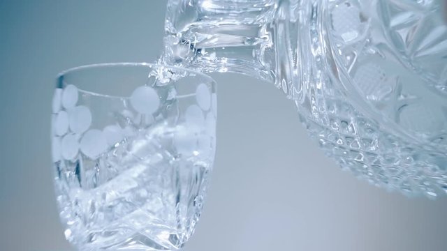 Vodka is poured from a glass decanter into a glass on white background. Macro. Closeup. Slow mo, slo mo, slow motion, high speed camera, 240fps, 250fps
