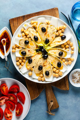 The leaves of Belgian endive with hummus, chickpeas and black olives. With strong olive oil of red pepperoncino and fresh cut tomatoes . Modern delicious food for vegetarians and gourmets.