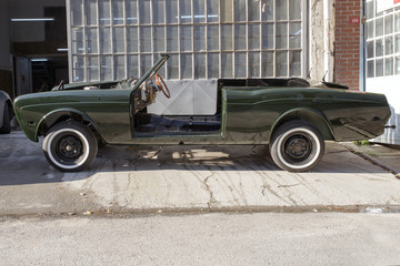 A luxury classic collectible car under restoration in the street