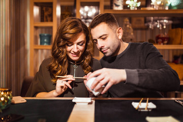 man pours soy sauce for his girlfriend in a restaurant