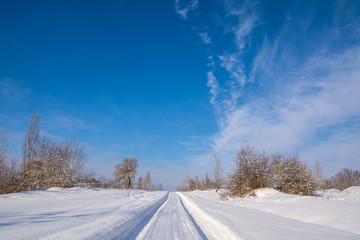 Countryside road through winter field with forest on a horizon. Artistic picture. Beauty world.