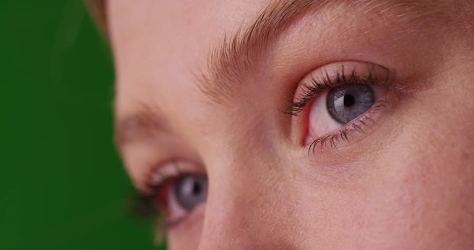 Close up of low angle view of Caucasian woman with blue eyes, looking off camera on grey background on green screen. On green screen to be keyed or composited. 