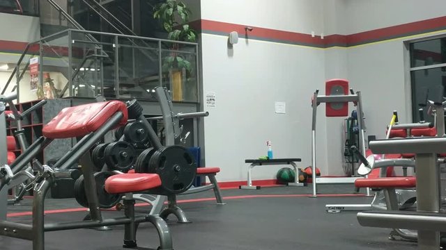 Empty gym facility with exercise equipment, weights, medicine ball racks shot at night.