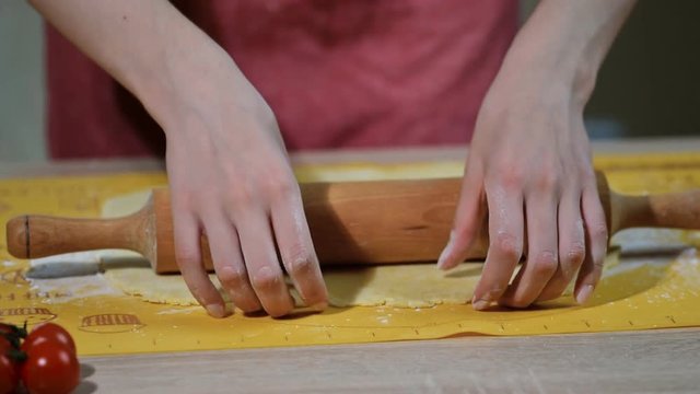 Woman's hands roll the dough.