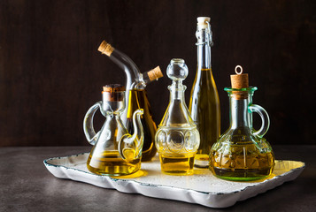 different shapes, types and sizes of cruets with olive oil on the table on a traydifferent shapes, types and sizes of cruets with olive oil on the table on a tray on dark