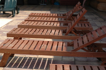 Several wooden sun loungers by the pool.