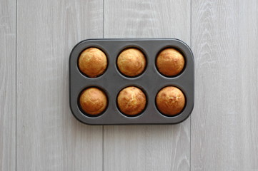 Simple cupcakes in a shape on a wooden background.