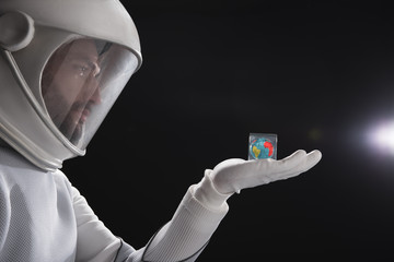 Side view profile of serious trained spaceman wearing helmet and protective costume is standing and...