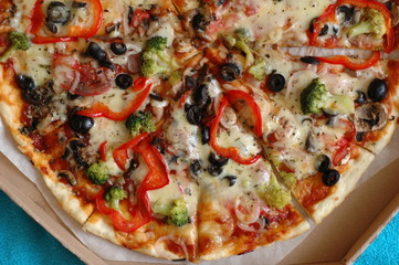 A large pizza in a cardboard box is a top view.