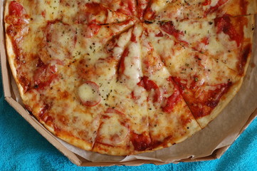 A large pizza in a cardboard box is a top view.